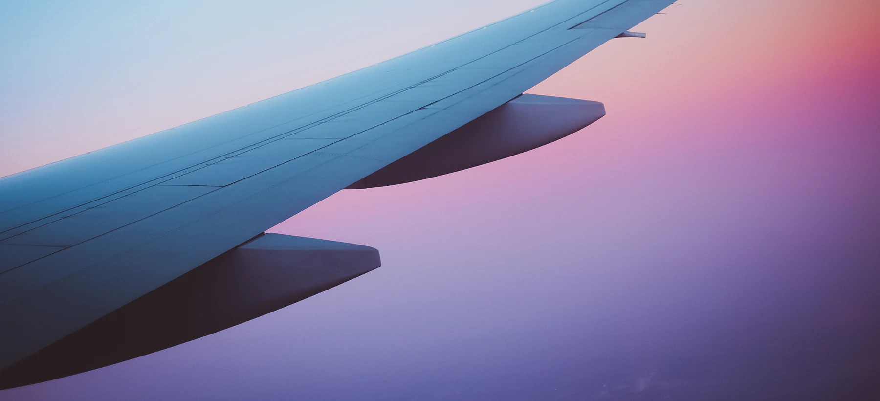 An aircraft wing above the clouds at sunset